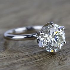 a round cut diamond sits on top of a wooden table