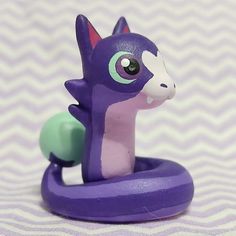 a purple pony toy sitting on top of a white and green object with black eyes