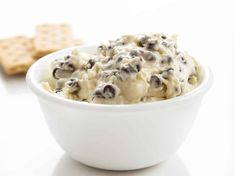 a white bowl filled with food next to crackers