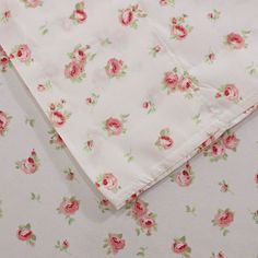 the fabric has pink flowers on it and is laying on top of white sheets with green leaves