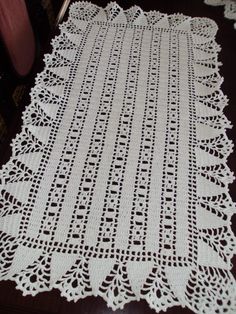 a white crocheted doily on a wooden table with a chair in the background