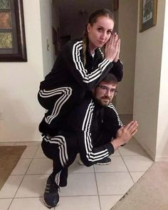 a man and woman posing for a photo in front of a door with their hands up