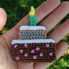 a small crocheted birthday cake ornament in someone's hand