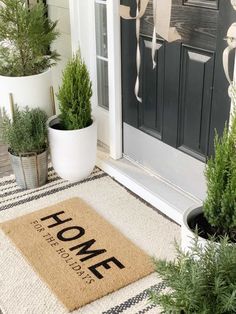 a welcome mat with the word home on it sits next to potted plants in front of a door