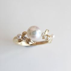 a pearl and diamond ring sitting on top of a white surface