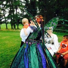 a woman dressed as a fairy with two children and an adult standing next to her