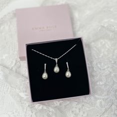 a necklace and earring set in a box on a lace tablecloth with a pink ribbon