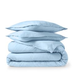 four pillows stacked on top of each other in light blue linens, with the covers folded down