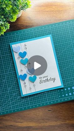 a birthday card with hearts on it sitting on top of a cutting board next to a potted plant