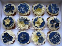 twelve cupcakes with blue and white frosting decorated with flowers, swirls and pearls