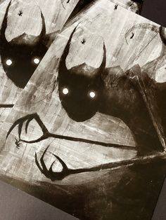 two pieces of artwork with eyes and horns drawn on the side of each piece in black and white