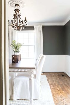 a dining room table with white chairs and a chandelier