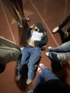 a group of people standing and sitting around each other with their feet on the ground