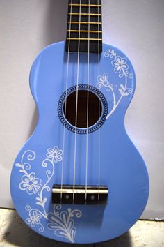 a blue ukulele with white flowers painted on it's body and strings