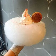 a person holding up a dessert in front of a tiled wall