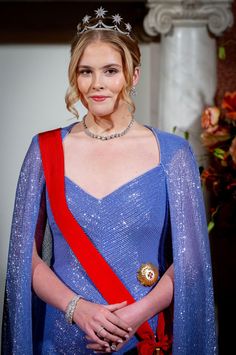 a woman in a blue dress with a red sash around her neck and wearing a tiara