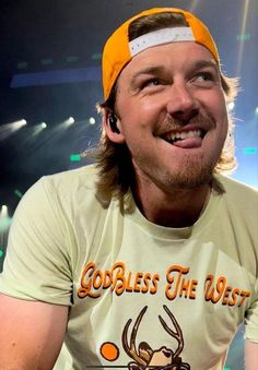 a man with a funny look on his face wearing an orange and white hat, smiling at the camera