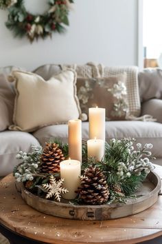 a tray with candles and pine cones on top of it in front of a couch