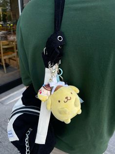 a person wearing a green shirt holding a yellow stuffed animal keychain