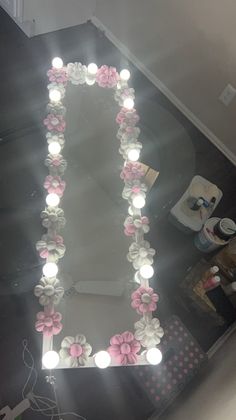 a lighted mirror with flowers on it in the shape of a letter i and some lights