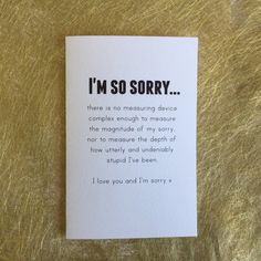 i'm so sorry card with black writing on it sitting on a gold surface