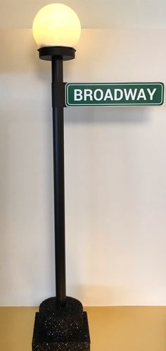 a street sign sitting on top of a black pole next to a white light fixture