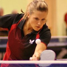 a woman is playing ping pong in a gym