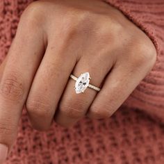 a woman's hand with a diamond ring on her finger and a pink sweater