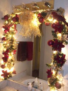 a bathroom decorated for christmas with lights on the mirror and decorations around the sink area