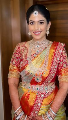 a woman in a red and yellow sari posing for the camera with her hands on her hips