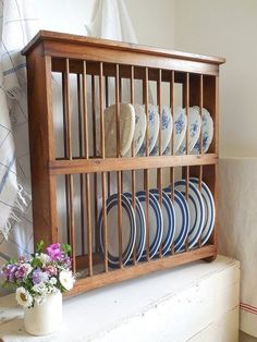 a wooden shelf with plates and vases on it next to a window sill