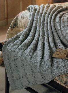 an image of a knitted blanket on top of a bed with the cover pulled over