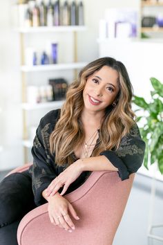 a woman sitting in a pink chair smiling at the camera