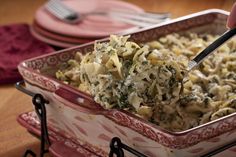 a casserole dish with pasta and spinach in it is being lifted by a fork