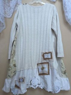 a white sweater with patches and laces hanging on a wall