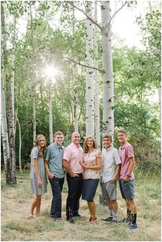 a group of people standing next to each other in front of some trees and grass