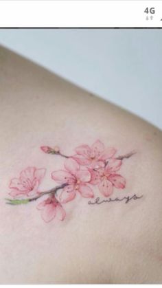 the back of a woman's shoulder with pink flowers on her left arm and words written in cursive writing