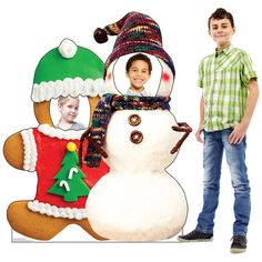 a young boy standing next to a large snowman and gingerbread man cutout