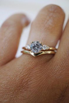 a woman's hand with a diamond ring on top of her finger and an engagement band