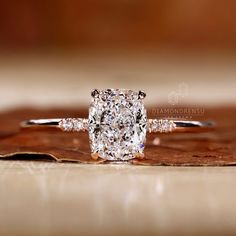 a cushion cut diamond ring sitting on top of a piece of wood