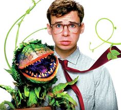 a man wearing glasses and a tie holding a fake dinosaur head