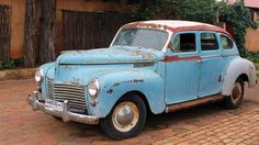 an old blue car is parked on the street