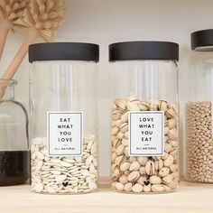 three glass jars filled with different types of nuts and beans on a shelf next to each other