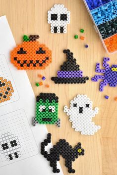 halloween themed perler beads are arranged on a wooden table next to an orange and black pumpkin