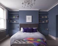 a bedroom with blue walls and gray carpeted flooring, a large bed in the center