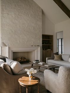 a living room with two couches and a table in front of a fire place