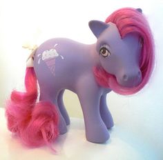 a toy pony with pink hair on a white surface