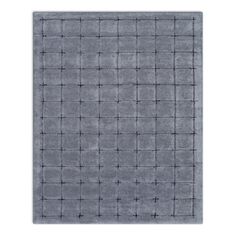 a gray rug with squares and crosses on the bottom, in front of a white background