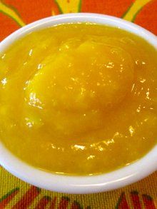 a small white bowl filled with yellow liquid on top of a colorful tablecloth covered table