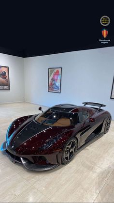 a very nice looking car on display in a room with some pictures hanging above it